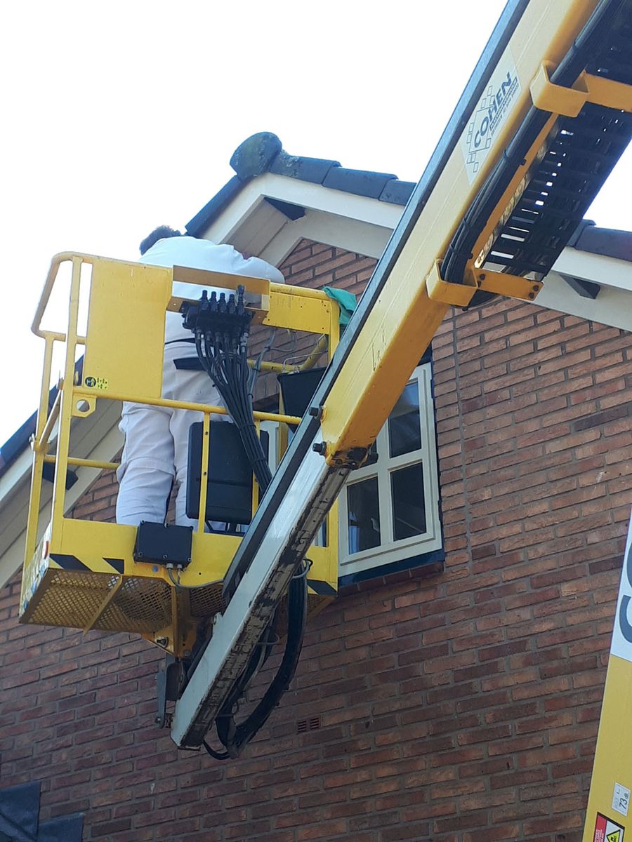 Schilderwerk aan de gevel en het houtwerk van een woning vanaf een hoogwerker